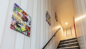 A staircase with striped walls and artwork, leading to an upper floor. - La Krasse Skytree (Tokyo)