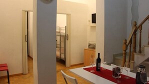 A dining area with a table set for two, a clock on the wall, and a staircase leading to another room. - Apartment in front of Plaza Mayor and Sol (Madrid)