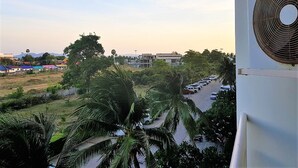 A view of a parking lot with cars, palm trees, and buildings in the background. - Jomtien Beach Condo - Studio Close to the Beach (Pattaya)