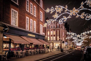A street with outdoor seating at a restaurant, brick buildings, and decorative lights. - Classy Apartment in the ♥️ of Marylebone ❄️ Air Conditioning | Sleeps 5 (Greater London)
