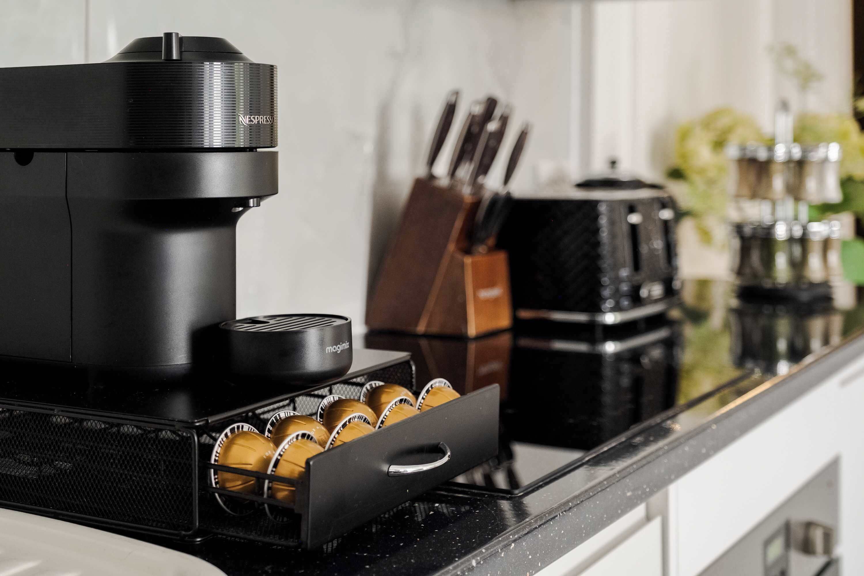 A kitchen with a coffee maker, a knife block, and a coffee machine on the counter.