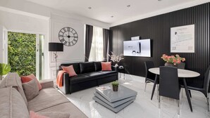 Ein modernes Wohnzimmer mit einer schwarzen Couch, einem Couchtisch und einem Essbereich mit rundem Tisch und Stühlen.