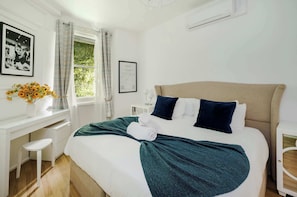 Un dormitorio ordenado con cama, escritorio y ventana con cortinas.