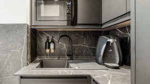 Een moderne keuken met een ingebouwde magnetron, een koffieapparaat en een gootsteen met een kraan.