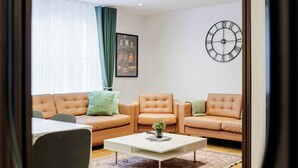 Uma sala de estar moderna com sofá, poltronas, mesa de centro e um relógio na parede.