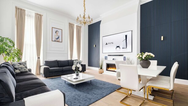 A modern living room with a sofa, coffee table, TV, fireplace, and dining area.