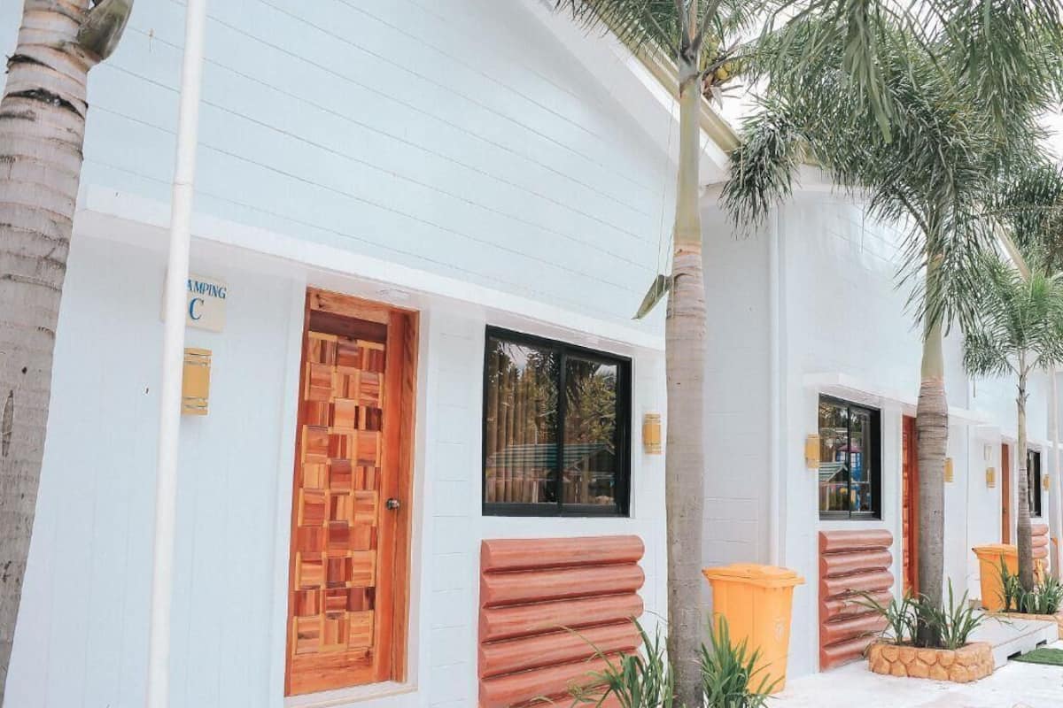 A row of hotel rooms with white walls, wooden doors, and windows.