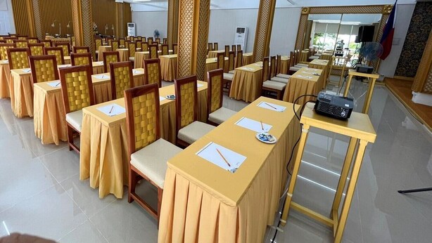 A conference room with rows of tables, chairs, and a podium. - Villa Excellance Beach & Wavepool Resort (Tanza)