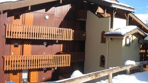 Un chalet en bois doté d’un balcon et dont le toit est recouvert de neige.
