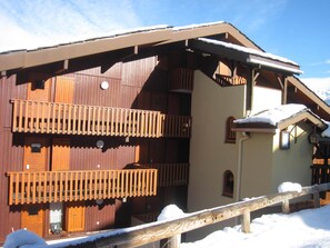 Een houten chalet met een balkon en een met sneeuw bedekte kap.