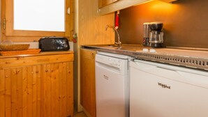 Une cuisine compacte avec des meubles en bois, un lave-vaisselle encastré, une machine à café et un grille-pain.