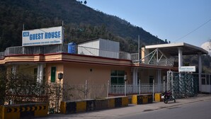 A guest house with a signboard, a motorcycle parked in front, and a mountainous backdrop. - AJK Guest House (Mekhtar)