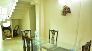 A dining area with a glass table and wooden chairs. - AJK Guest House (Mekhtar)