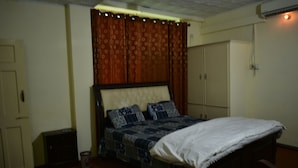 A bedroom with a bed, a wardrobe, and a small cabinet. - AJK Guest House (Mekhtar)
