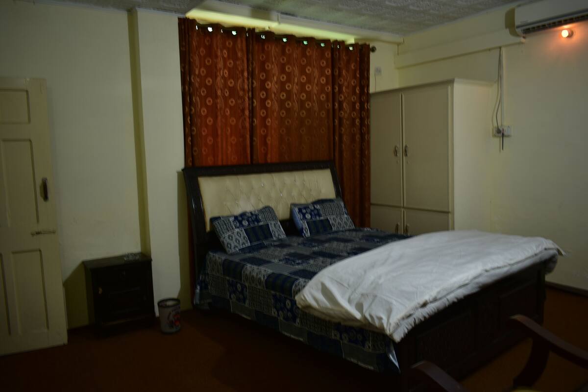 A bedroom with a bed, a wardrobe, and a small cabinet.