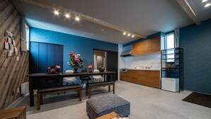 A modern kitchen with wooden cabinets, a white refrigerator, and a dining area with a bench and chairs. - THE PLAZA HOTEL S4W12 (Sapporo)