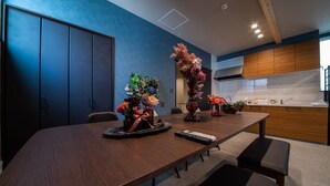 A modern dining area with a long wooden table, chairs, and a vase of flowers. - THE PLAZA HOTEL S4W12 (Sapporo)