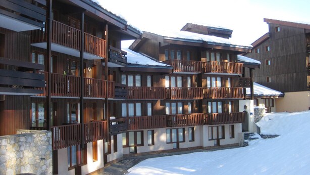 Ein mehrstöckiges Hotel mit Balkonen und einem mit Schnee bedeckten Gelände.