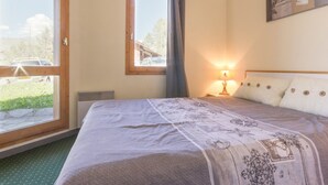Ein Schlafzimmer mit Bett, Fenster, Nachttisch und Lampe.