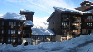 Ein schneebedecktes Gebäude mit mehreren Balkonen und einem Steinsockel, umgeben von Schnee.
