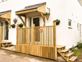 Una terraza de madera con un letrero que dice "Roberts Warren", una puerta y plantas en macetas.