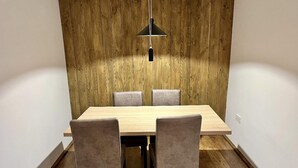Comedor con pared de madera, una mesa y cuatro sillas.