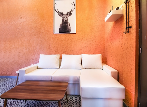 A modern room with a white sofa, a wooden coffee table, and a framed deer head artwork on the orange textured wall.