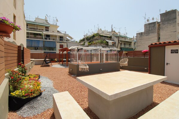 A rooftop terrace with a seating area, a small garden, and a view of surrounding buildings.
