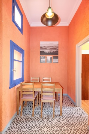 A dining area with a wooden table and chairs, a patterned floor, and a ceiling light fixture.