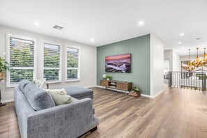 A modern living room with a grey sofa, a flat-screen TV, and a wooden cabinet.