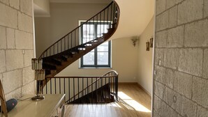 Eine Wendeltreppe mit Holzstufen und schwarzen Geländern, die zu einer oberen Etage führt.