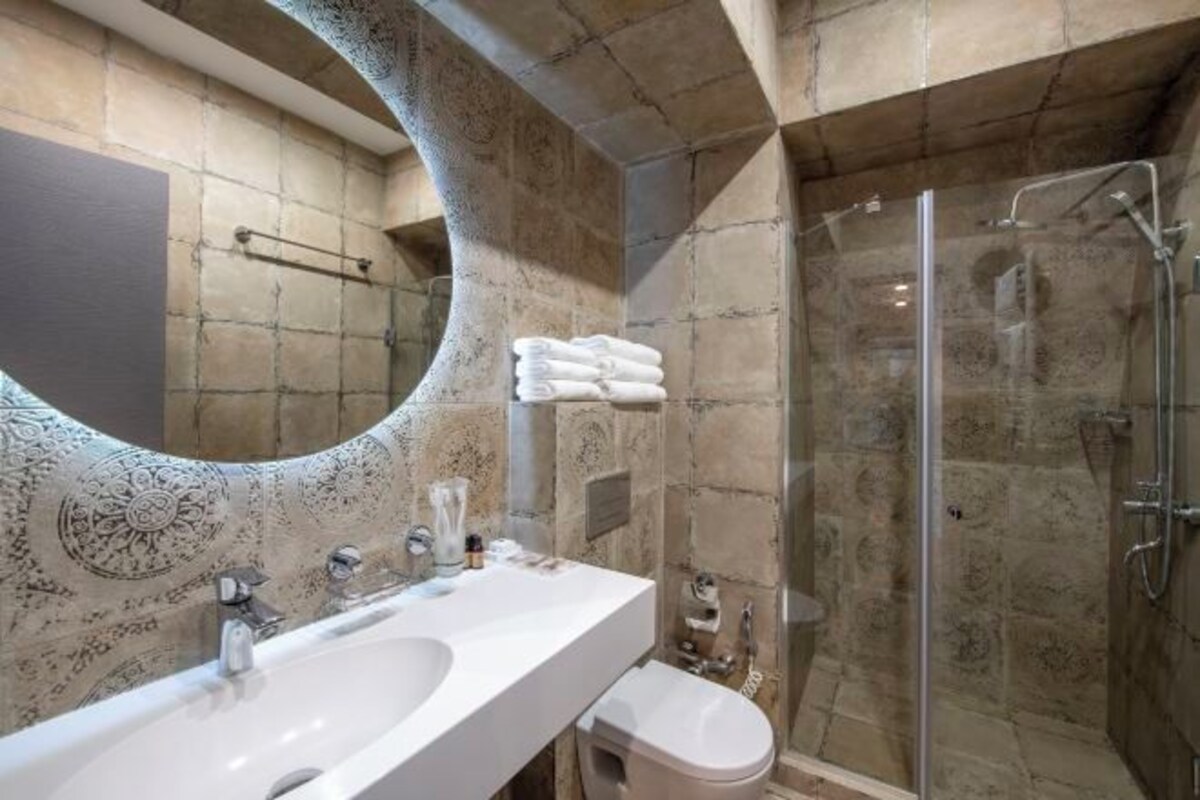 Une salle de bain dotée d’un grand miroir, d’un lavabo, de toilettes et d’une douche à parois de verre.