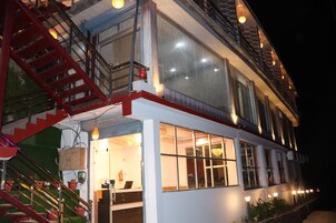 Un edificio de dos pisos con una escalera roja, ventanas grandes e iluminación exterior.