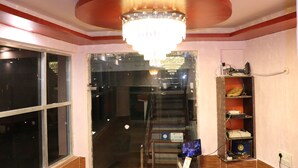 Ein Hotelzimmer mit einer Chandelüstere, einer Treppe und einem Regal mit Gegenständen.