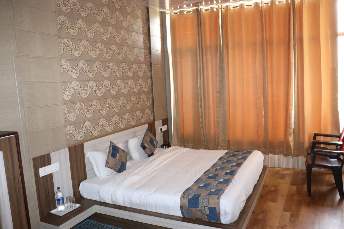 Une chambre d’hôtel avec un grand lit, une tête de lit en bois, un mur à motifs et une fenêtre avec des rideaux.