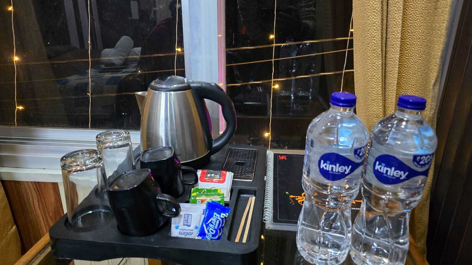 A breakfast trolley with a kettle, cups, sugar packets, and bottled water.