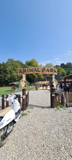 Señal para un parque de animales, con una verja de madera y una patineta estacionada al frente.