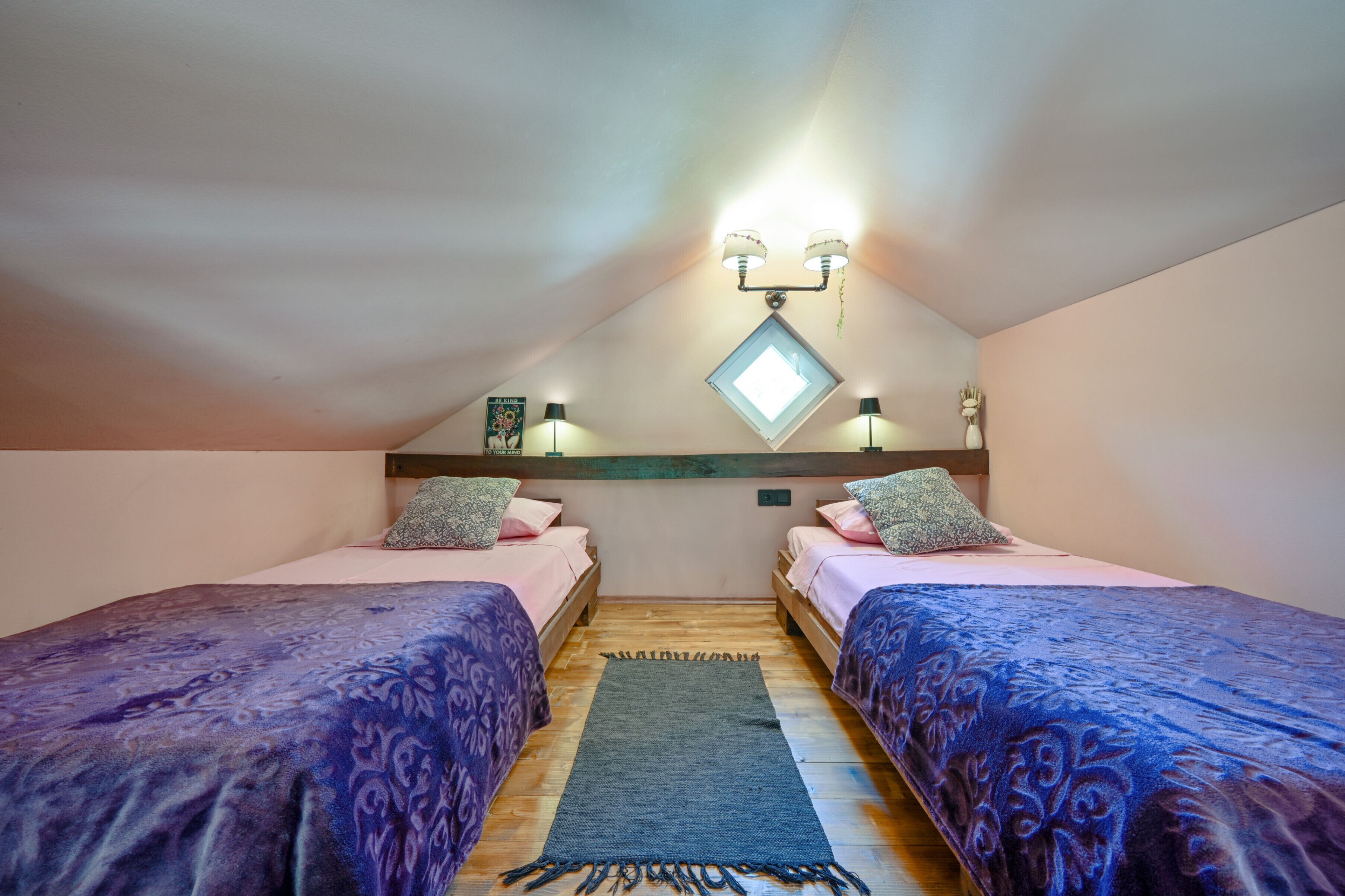 A bedroom with two beds, a skylight, and a wooden ceiling.