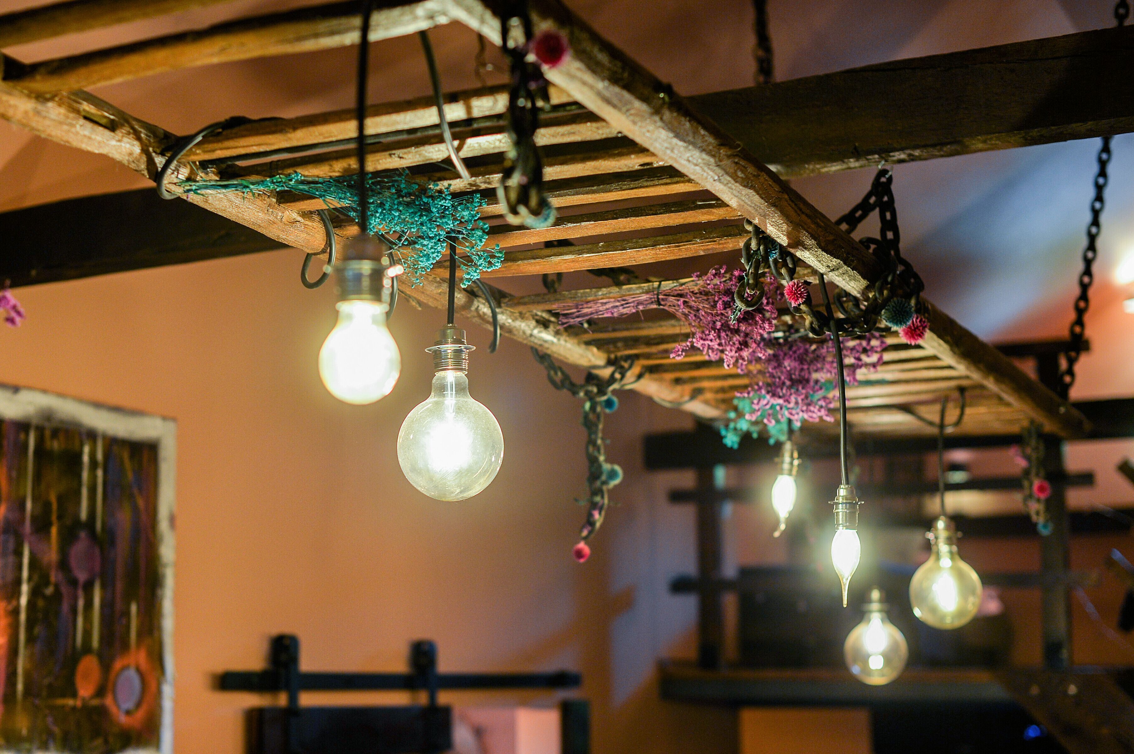 Un interior rústico con vigas de madera a la vista y bombillas colgantes.
