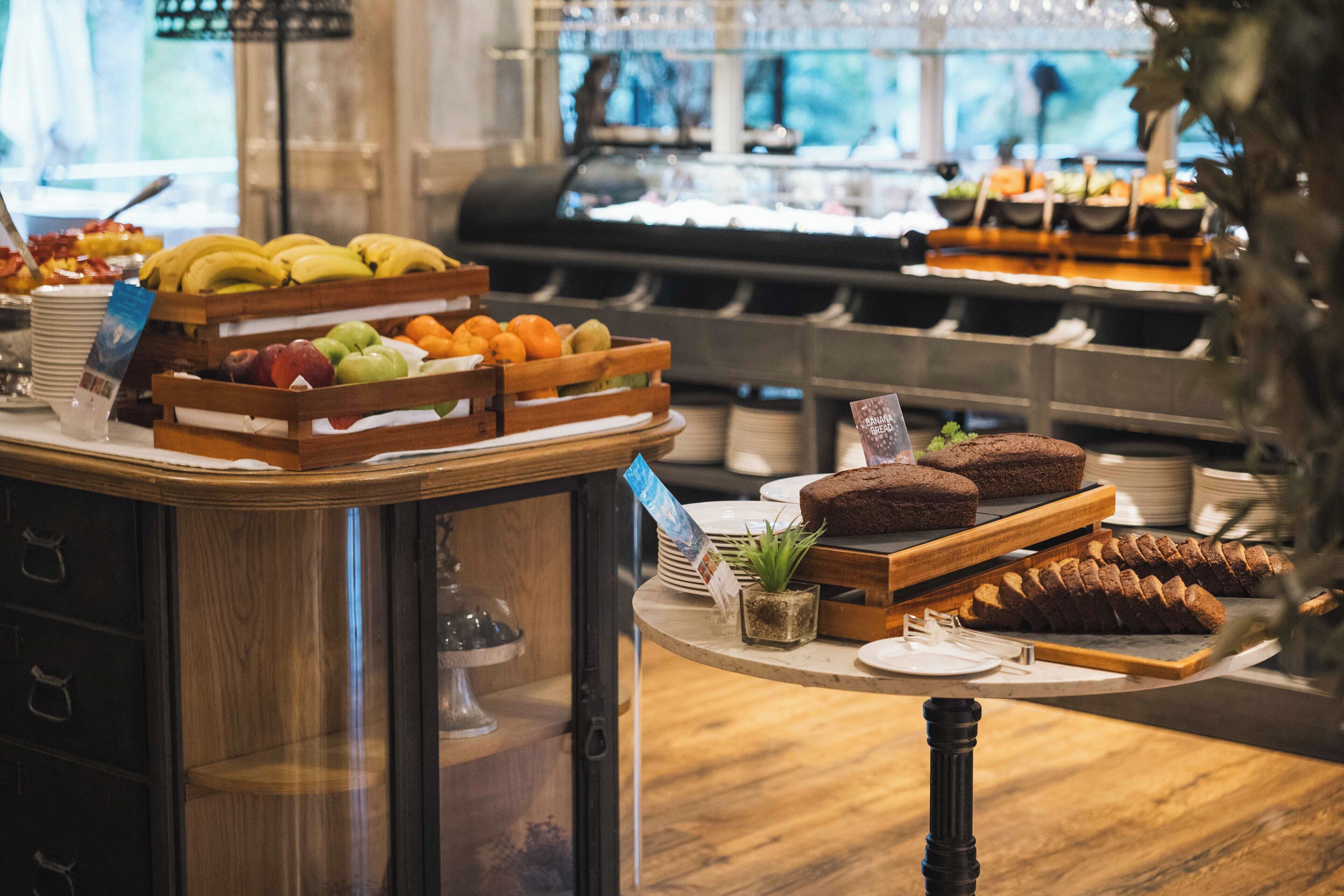 A buffet with various fruits, pastries, and a coffee station.