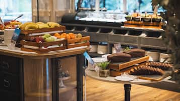 A buffet with various fruits, pastries, and a coffee station.