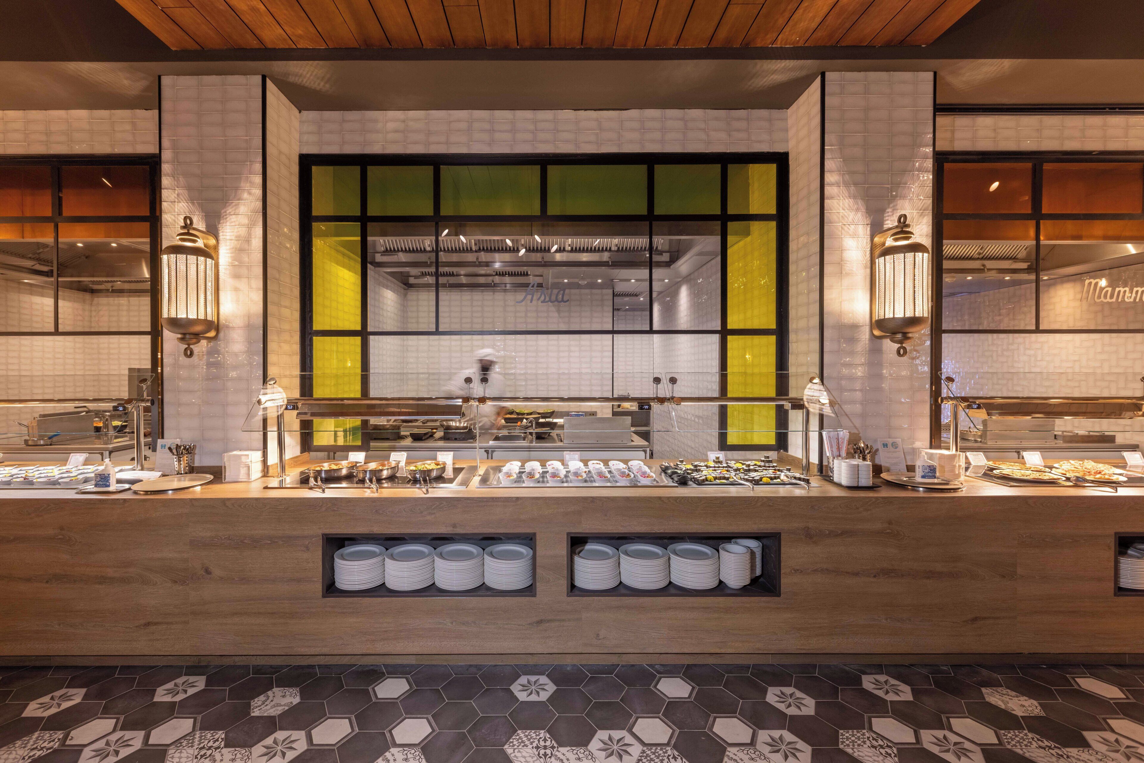 A buffet setup with a central counter, overhead lighting, and a tiled backsplash.