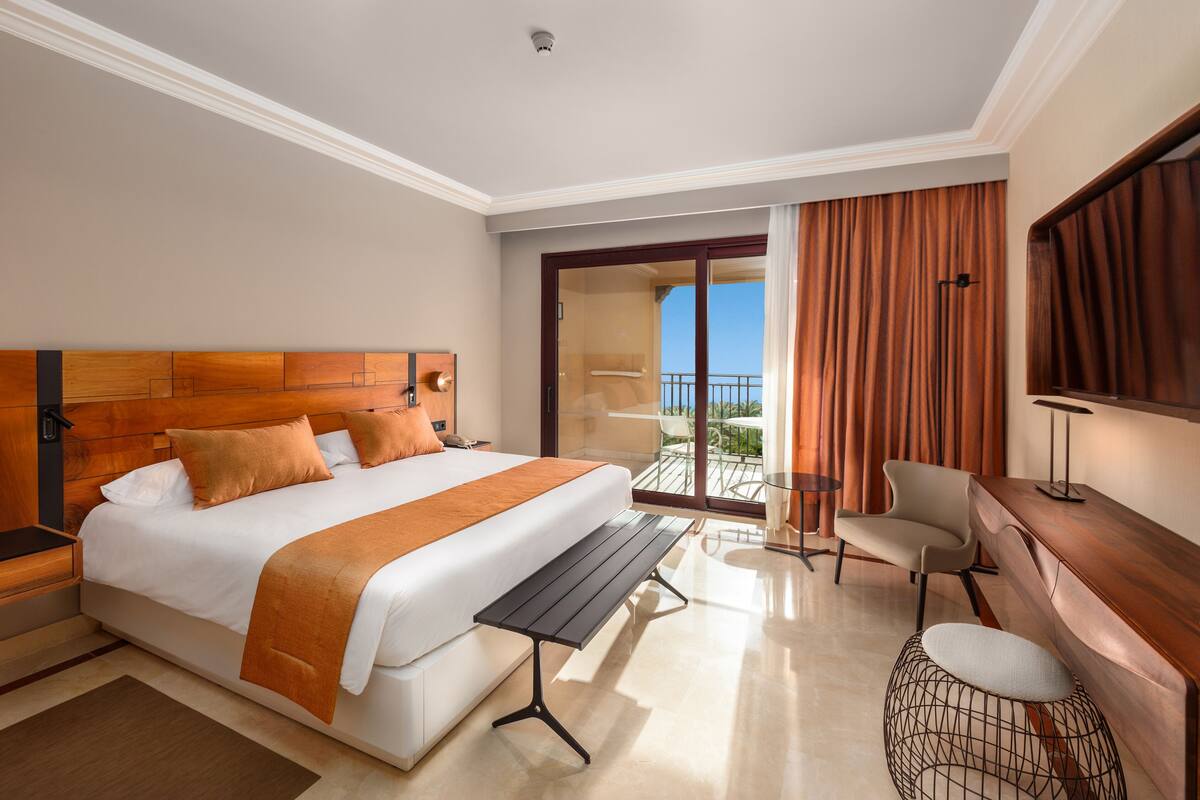 Une chambre d’hôtel avec un grand lit, un bureau, une chaise et un balcon avec vue.