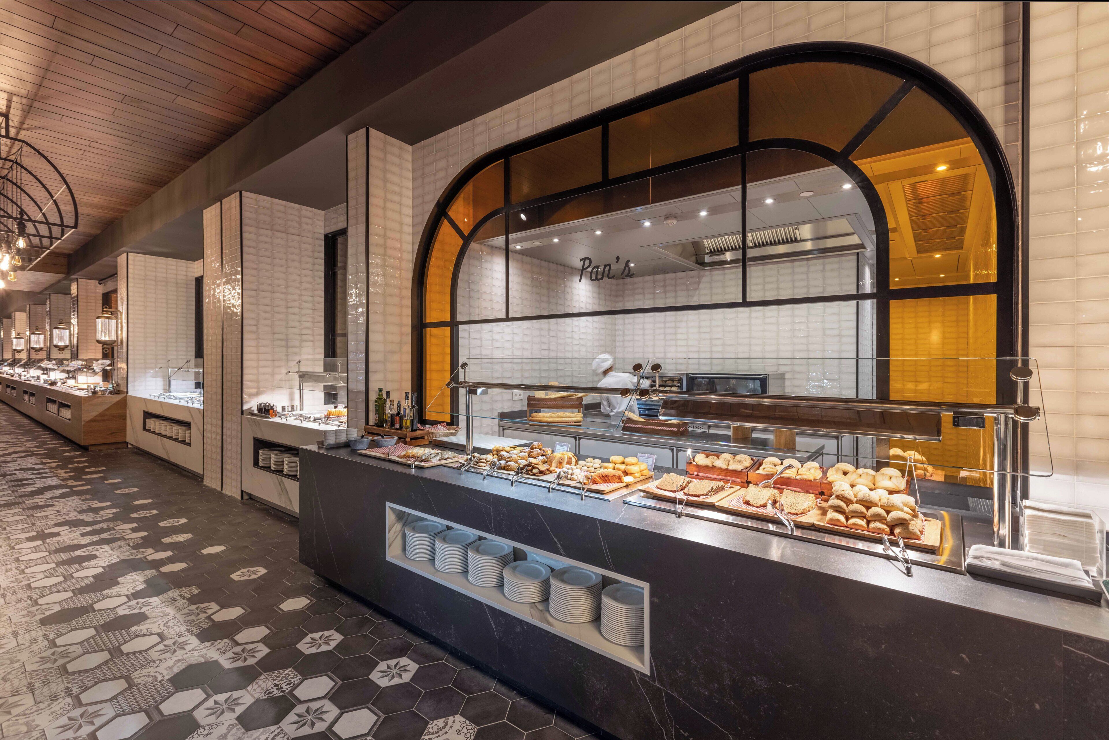 A buffet counter with various food items, a tiled floor, and a modern interior design.