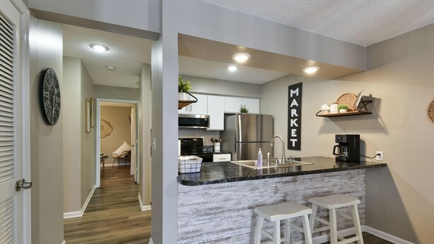 A modern kitchen with a marble countertop, stainless steel appliances, and a 'MARKET' sign on the wall.