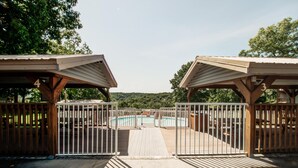 Zona de piscina cercada con muelle de madera y dos cobertizos.