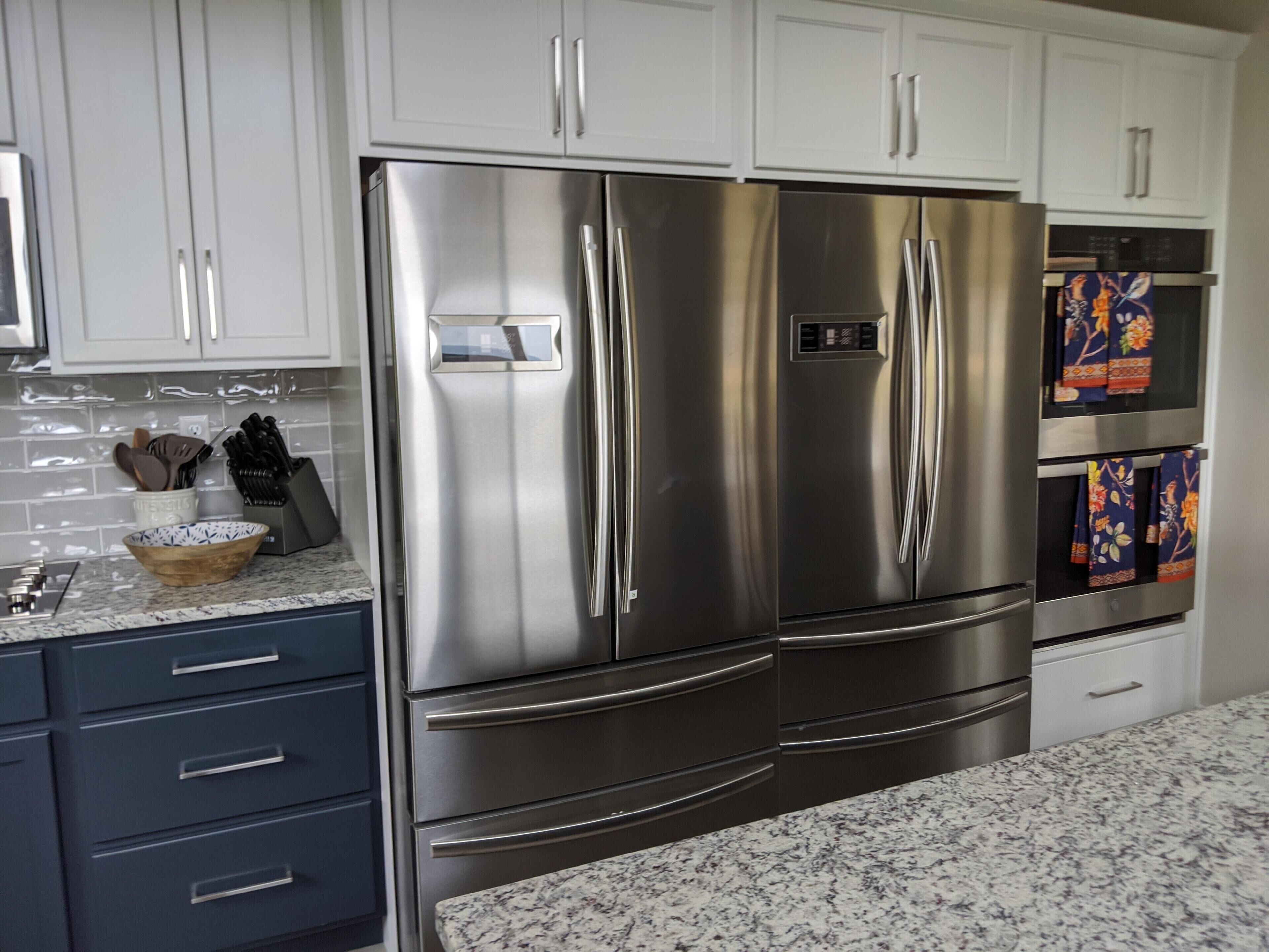 A modern kitchen with stainless steel appliances, white cabinets, and granite countertops.
