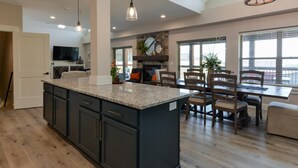 A spacious kitchen with a large island, dark cabinetry, and a stone fireplace. - Journey's Remedy Lite - Lake View - Closest to Indoor Pool - Sleeps 22 (Branson)