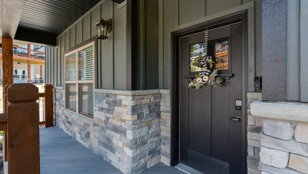 A stone-clad entrance with a dark door, a small porch, and a window with blinds. - Journey's Remedy Lite - Lake View - Closest to Indoor Pool - Sleeps 22 (Branson)