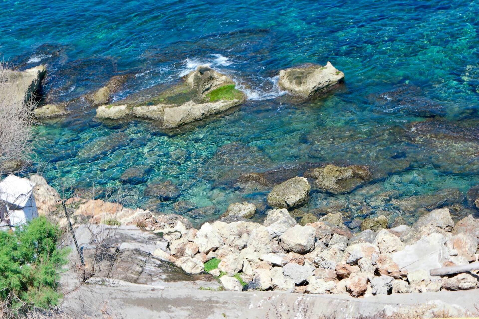 A rocky shoreline with clear blue water.